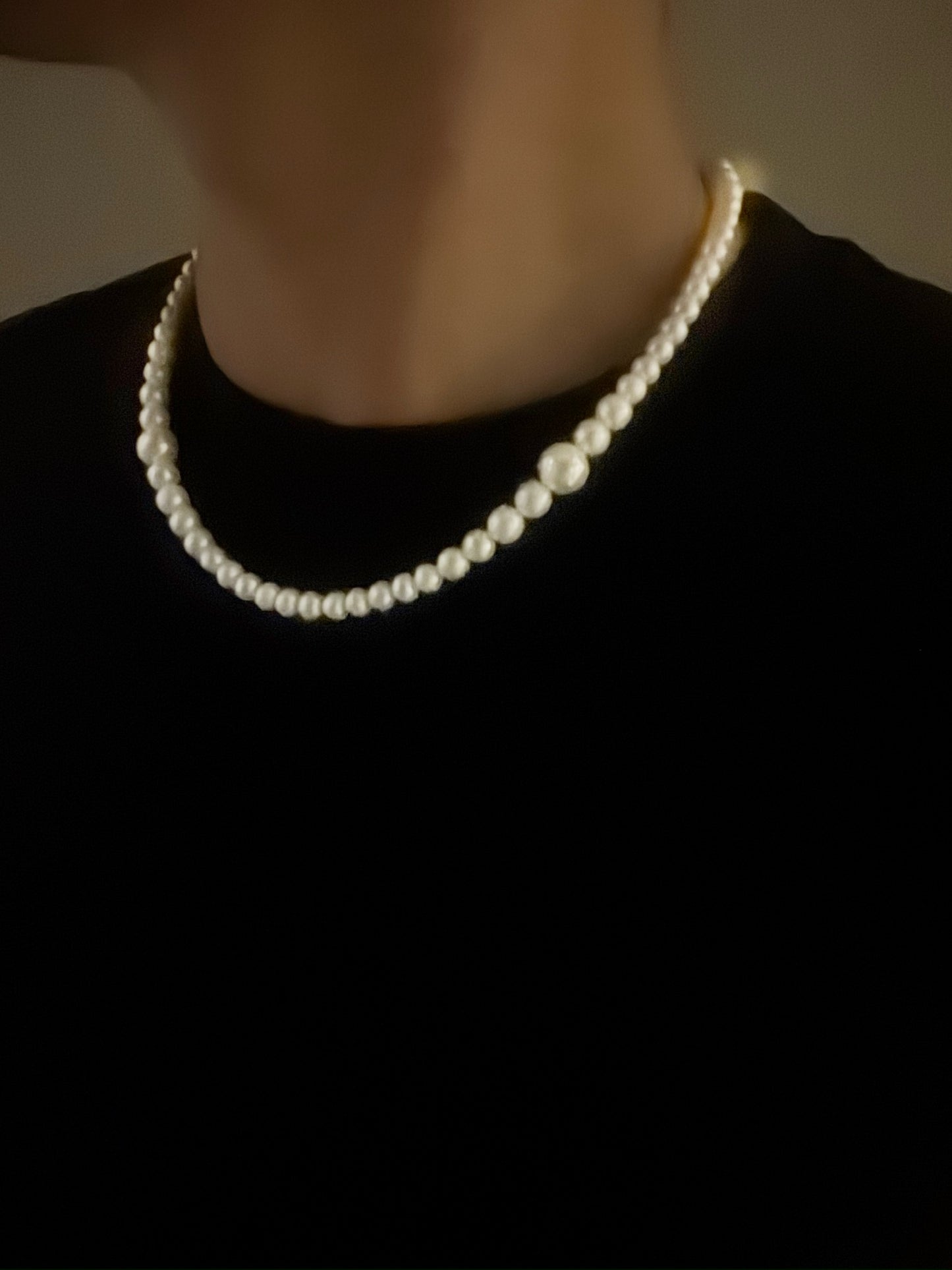 White freshwater pearl necklace worn by a person against a black background