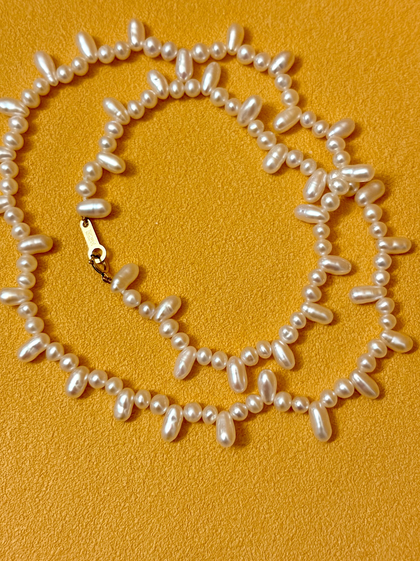 Aurora Luster Wild Keshi Pearl Choker Necklace featuring natural pearls on orange background.