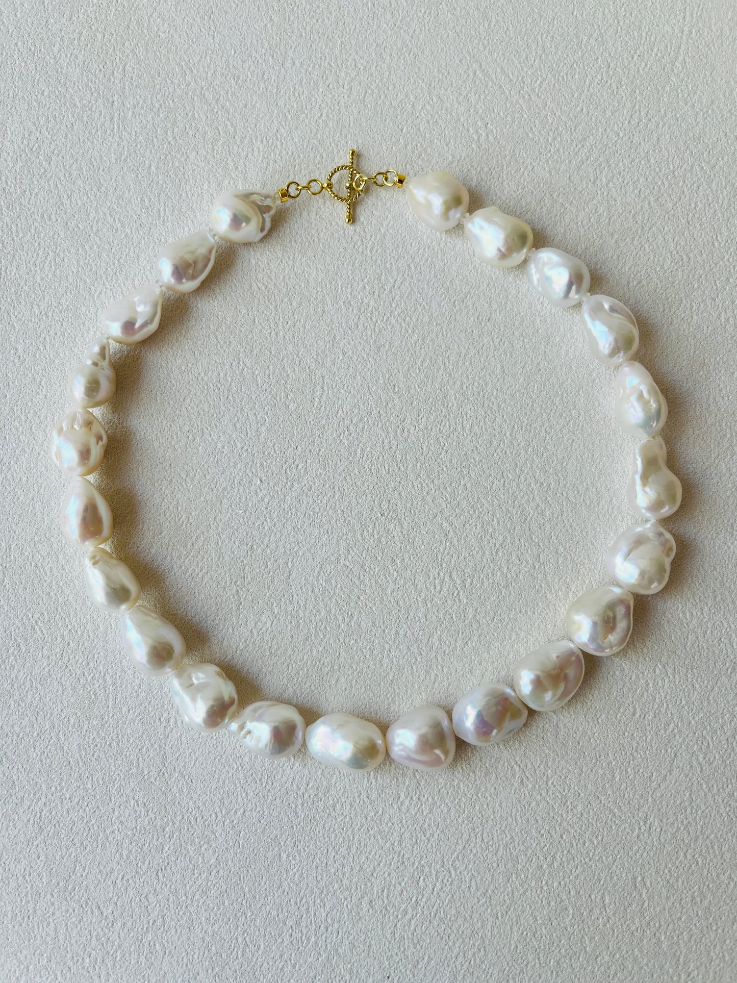 Baroque pearl necklace featuring unique baroque pearls and 24K gold vermeil detailing on a light background.