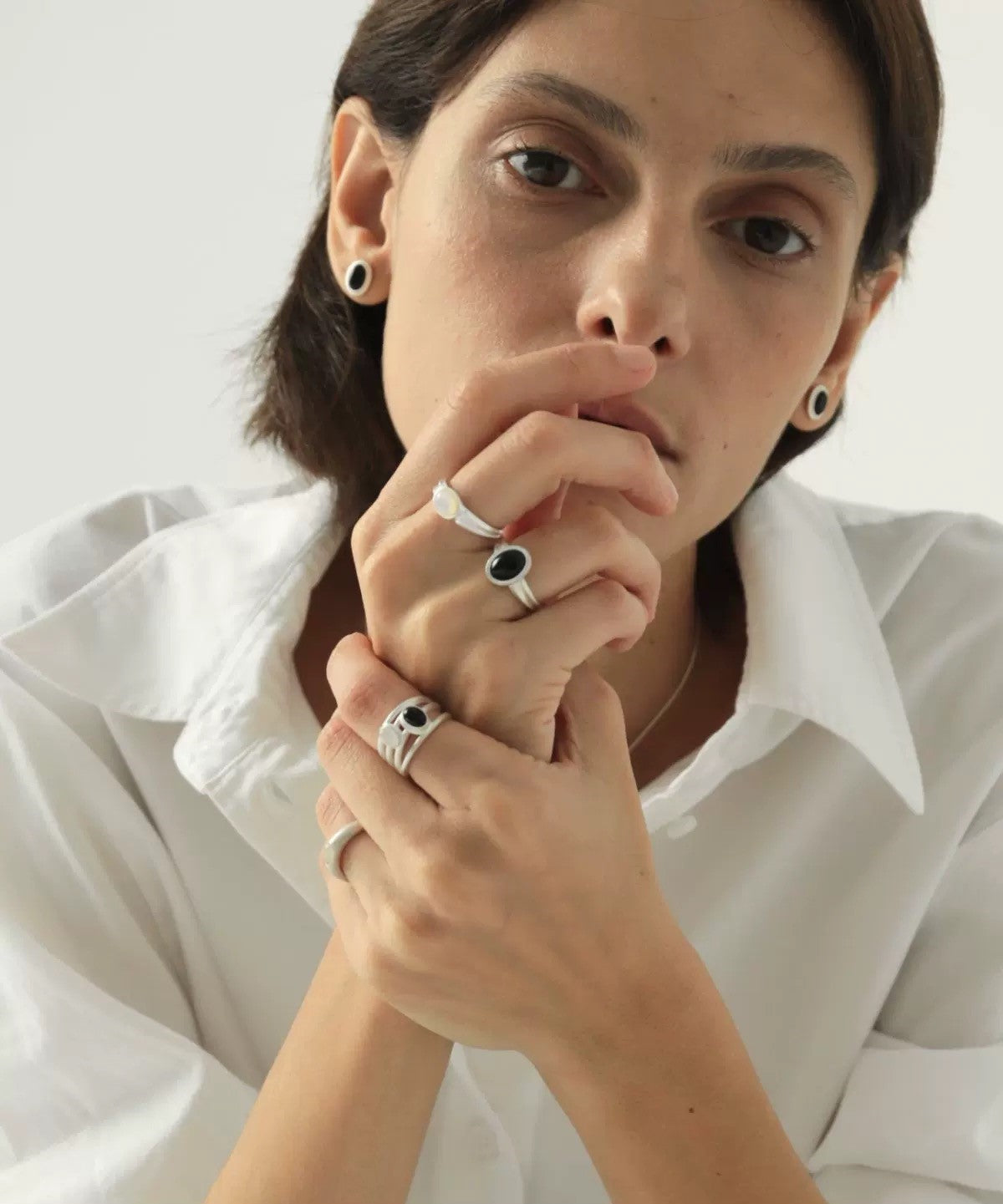 Person wearing multiple rings on a plain background