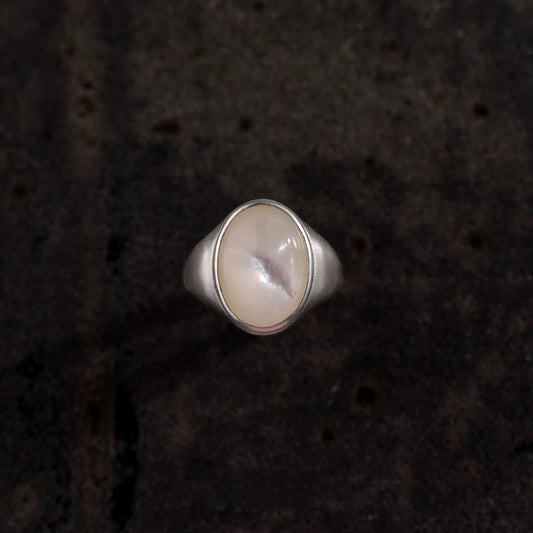 Silver ring with a round stone on a dark textured background