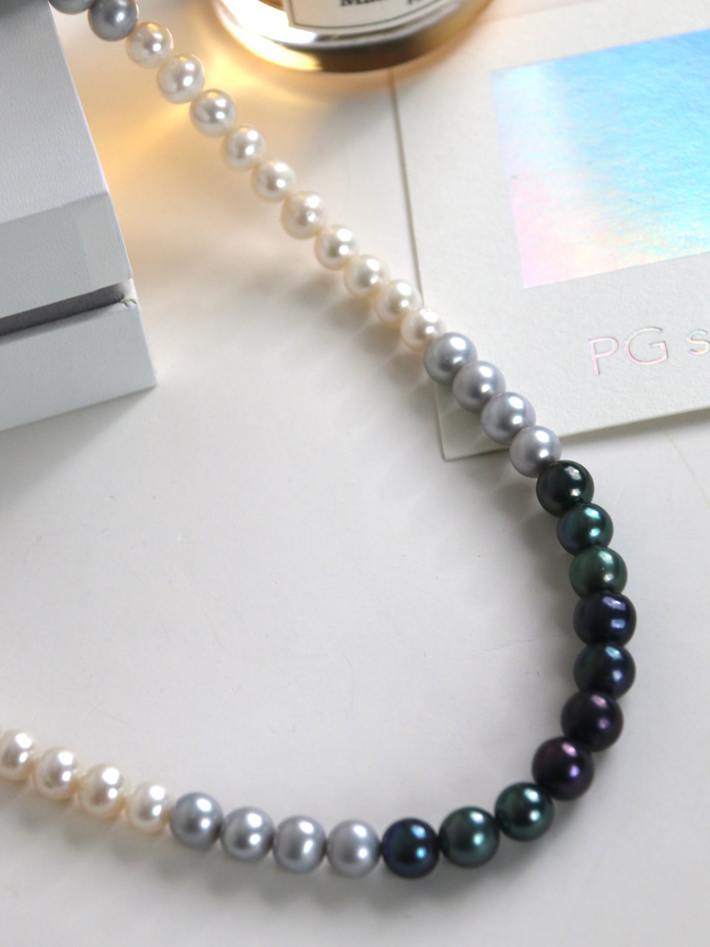 Pearl necklace for men with black and white freshwater pearls on a light surface