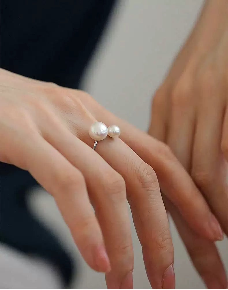 Pearl ring on a finger with a blurred background
