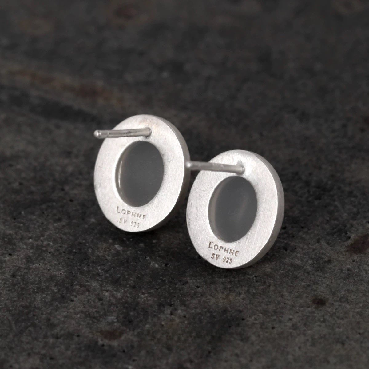 Silver earrings with black stones on a dark textured background