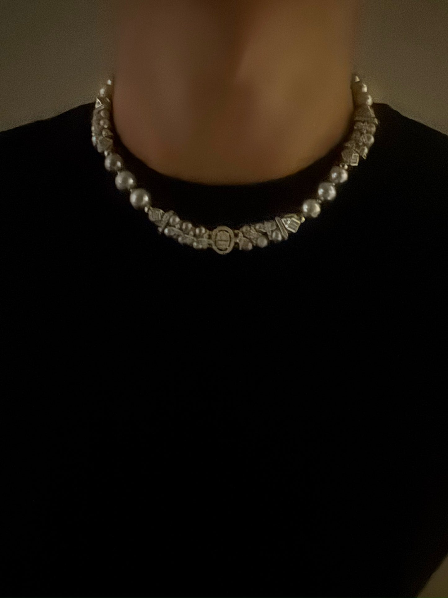 Silver beaded pearl necklace on a plain background