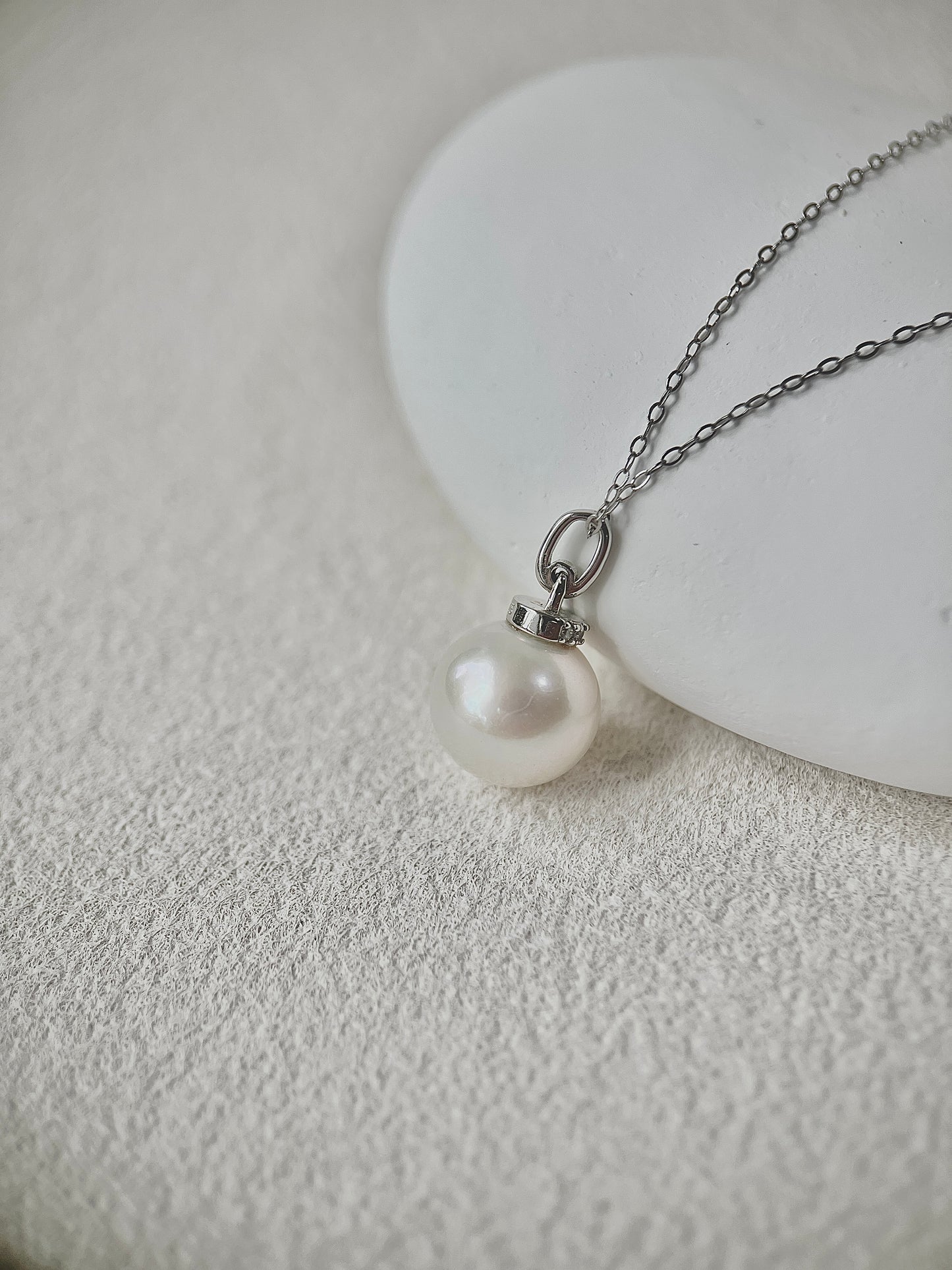 Pearl Pendant necklace with silver chain on a textured white surface