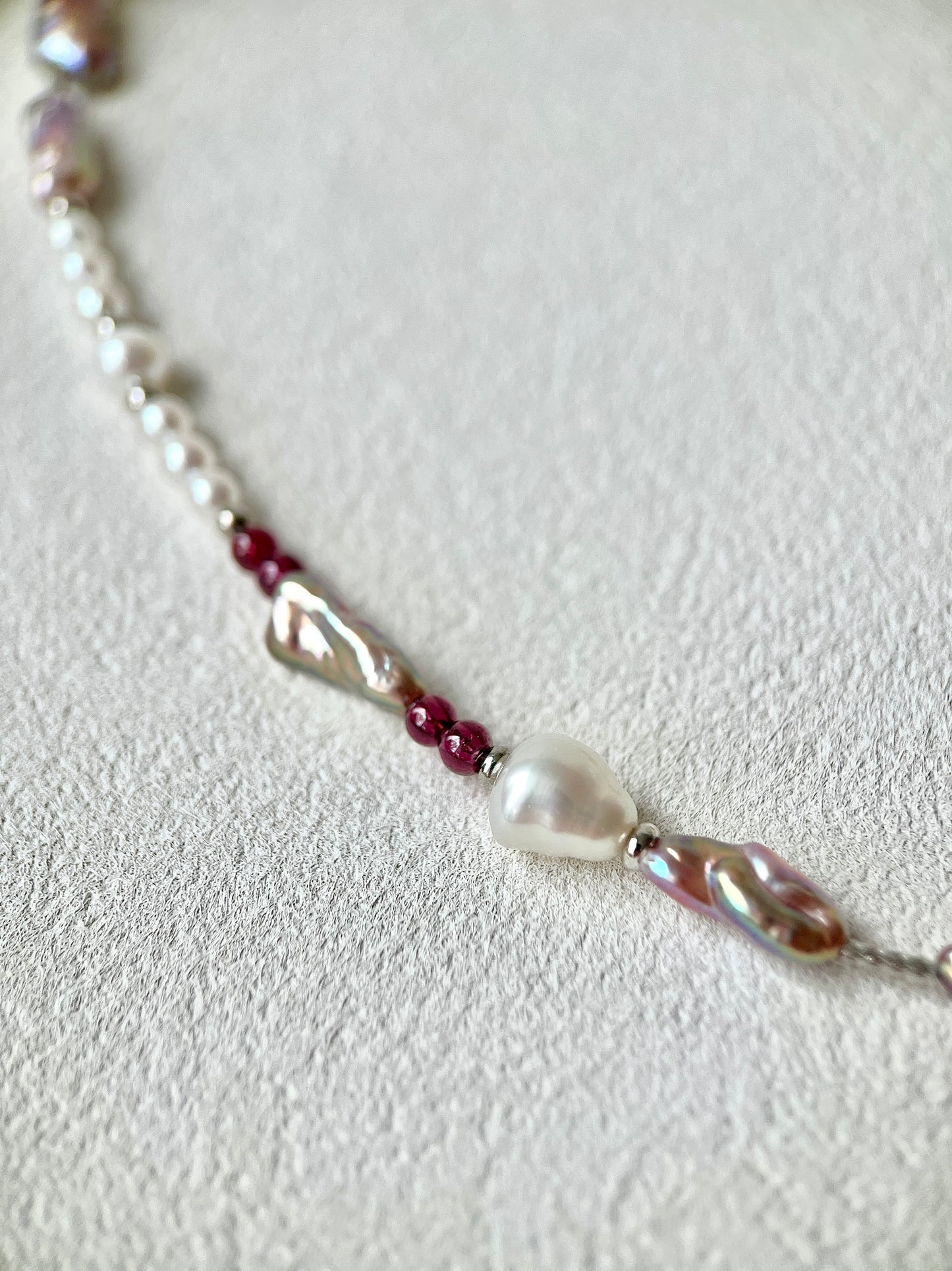 Necklace with pearls and red beads on a light gray background