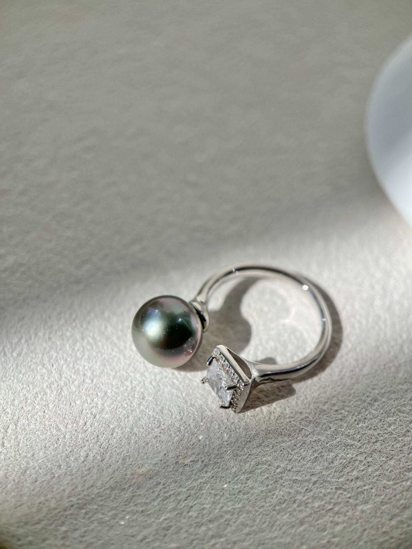 Silver ring with a black Tahitian pearl on a light gray surface