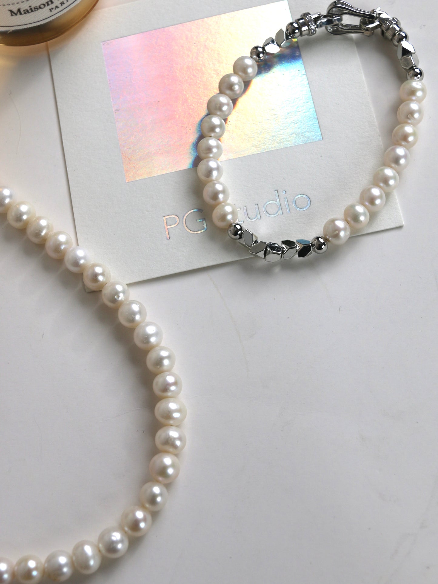 Pearl necklace and bracelet for men on a white surface with 'PG studio' card.