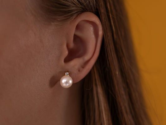 Close-up of an ear wearing a pearl earrings with a blurred background