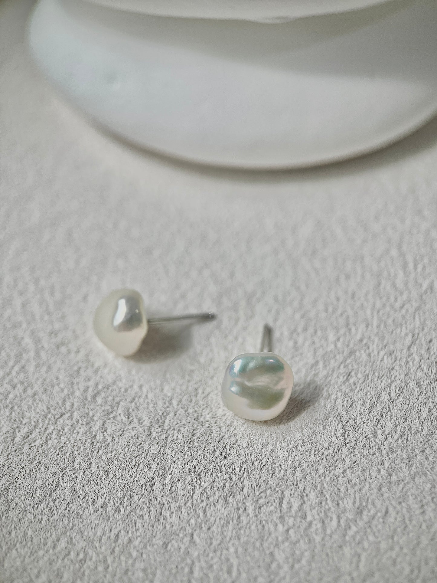 Pearl earrings on a textured white surface