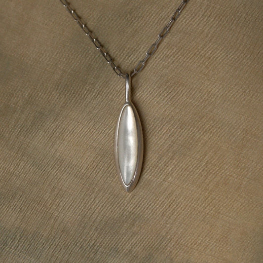 Silver nacre pendant necklace on a beige fabric background