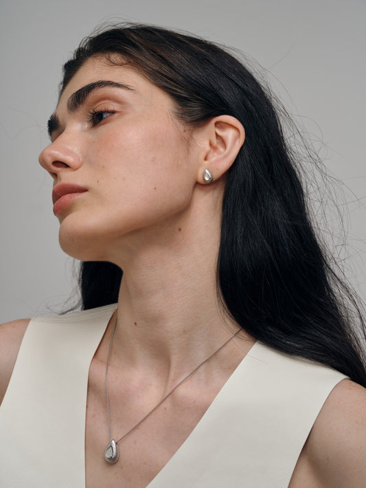 Woman wearing a necklace and earrings with agate gemstones against a neutral background