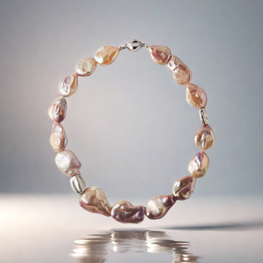 Pearl necklace with a silver clasp on a reflective surface with a gray background