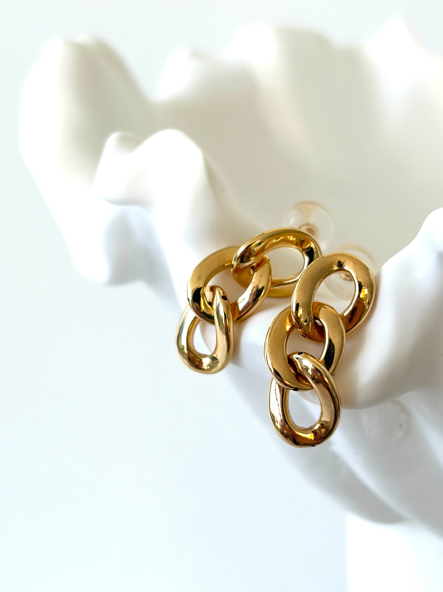 18k Gold Earrings - Chloe - Stylish Chain Earrings with interlocking design resting on a white hand sculpture.