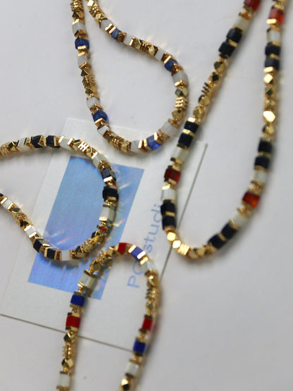 Men Necklaces with gold, black, and red beads on a white surface