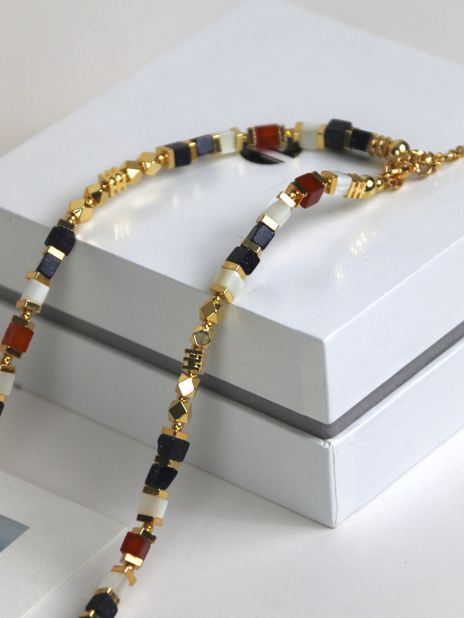 Necklace for men with gold, black, and red agate on a white surface