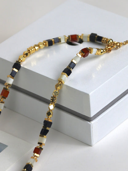 Necklace for men with gold, black, and red agate on a white surface