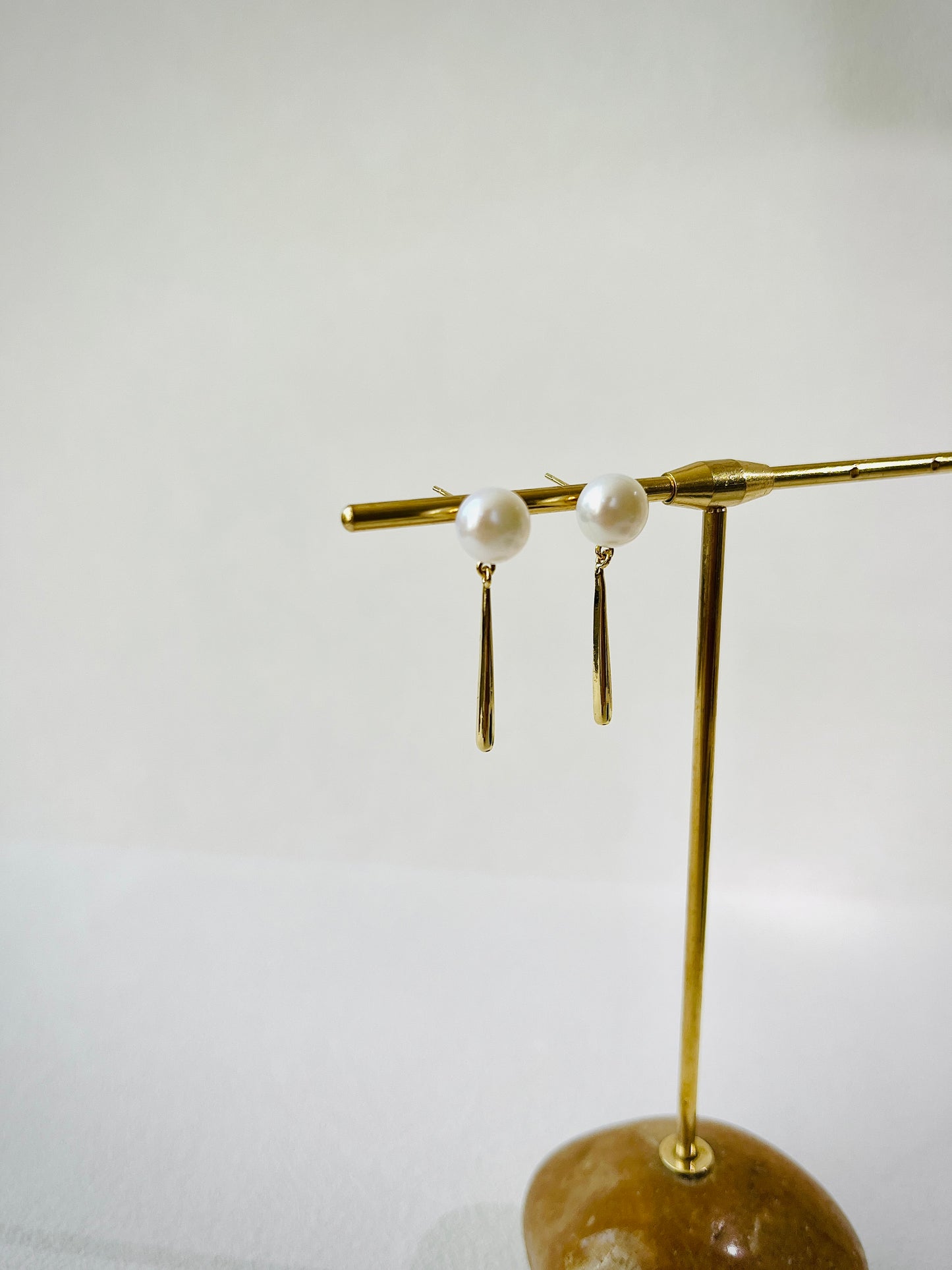 Gold earring on a stand with a white background