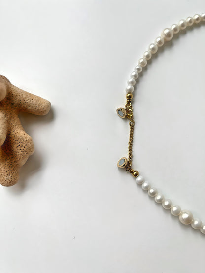 Pearl necklace strand with gold clasp on a white background