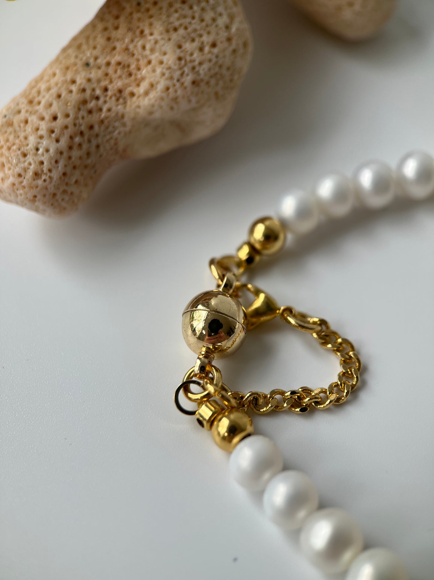 Pearl necklace with gold clasp on a white background