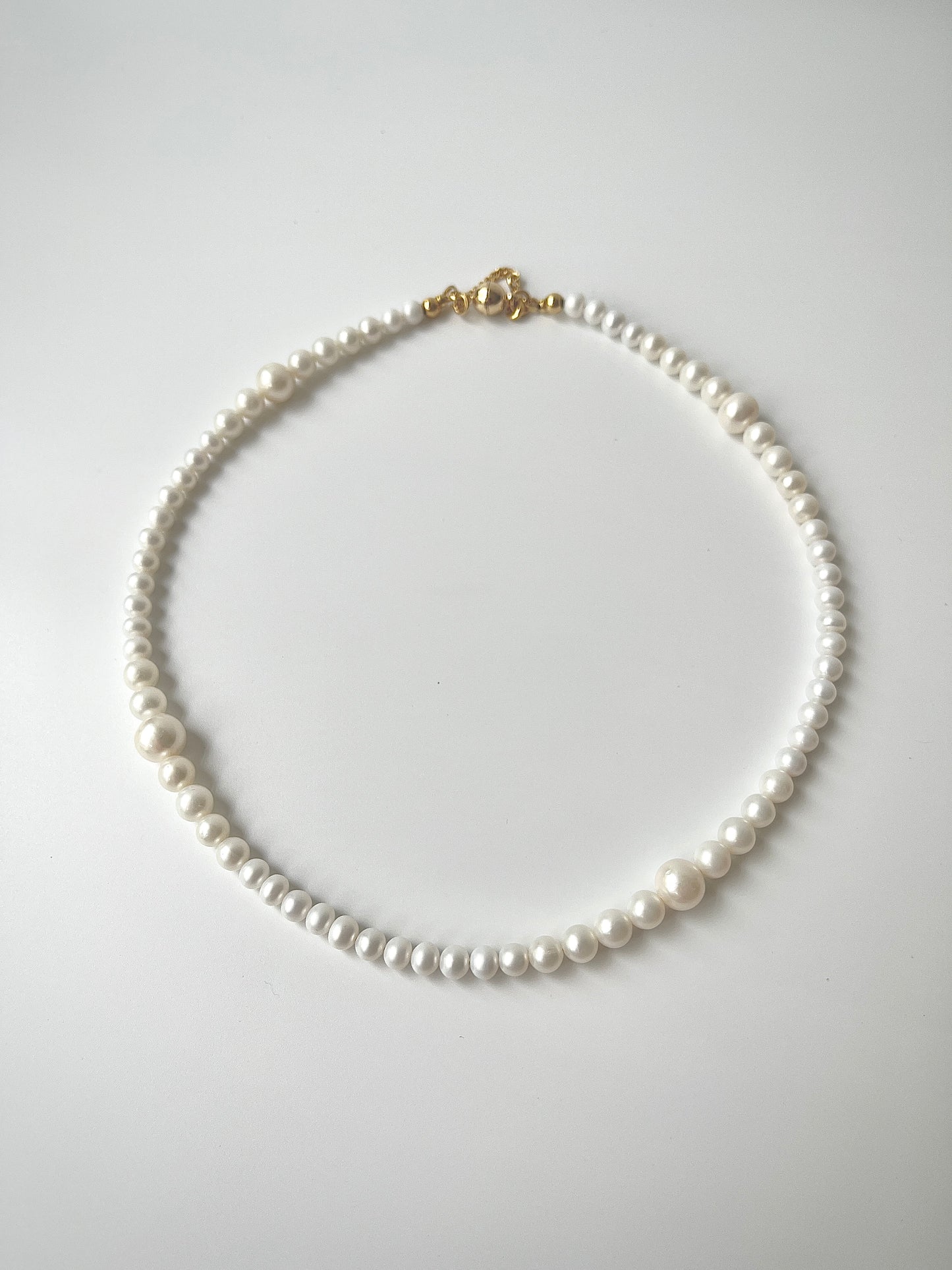 White freshwater pearl necklace strand on a light gray background