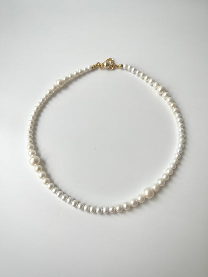 White freshwater pearl necklace strand on a light gray background