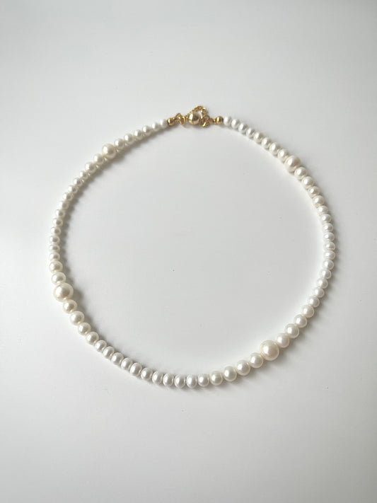 White freshwater pearl necklace strand on a light gray background