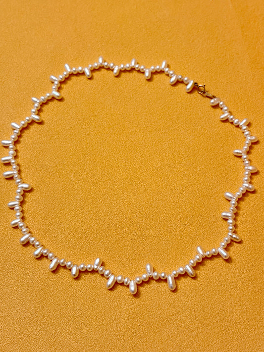 Aurora Luster Wild Keshi Pearl Choker Necklace featuring baroque shaped pearls on a vibrant orange background.