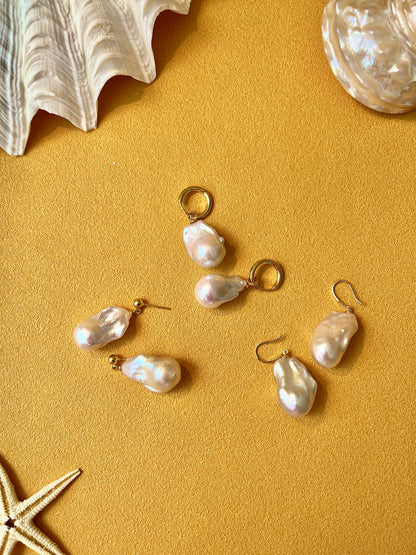 Baroque  Pearl earrings on a gold surface with seashells and starfish.