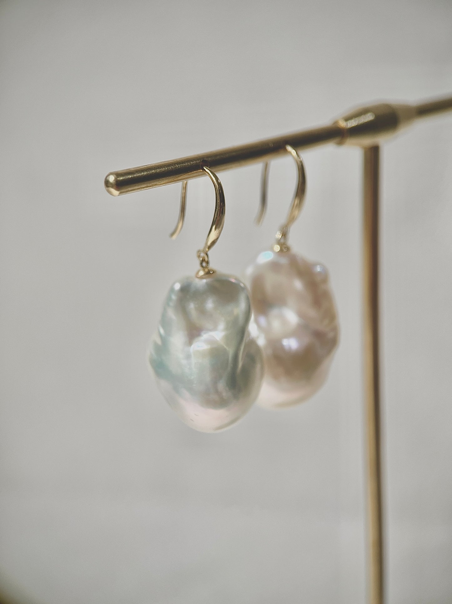 Pearl earrings on a stand against a neutral background