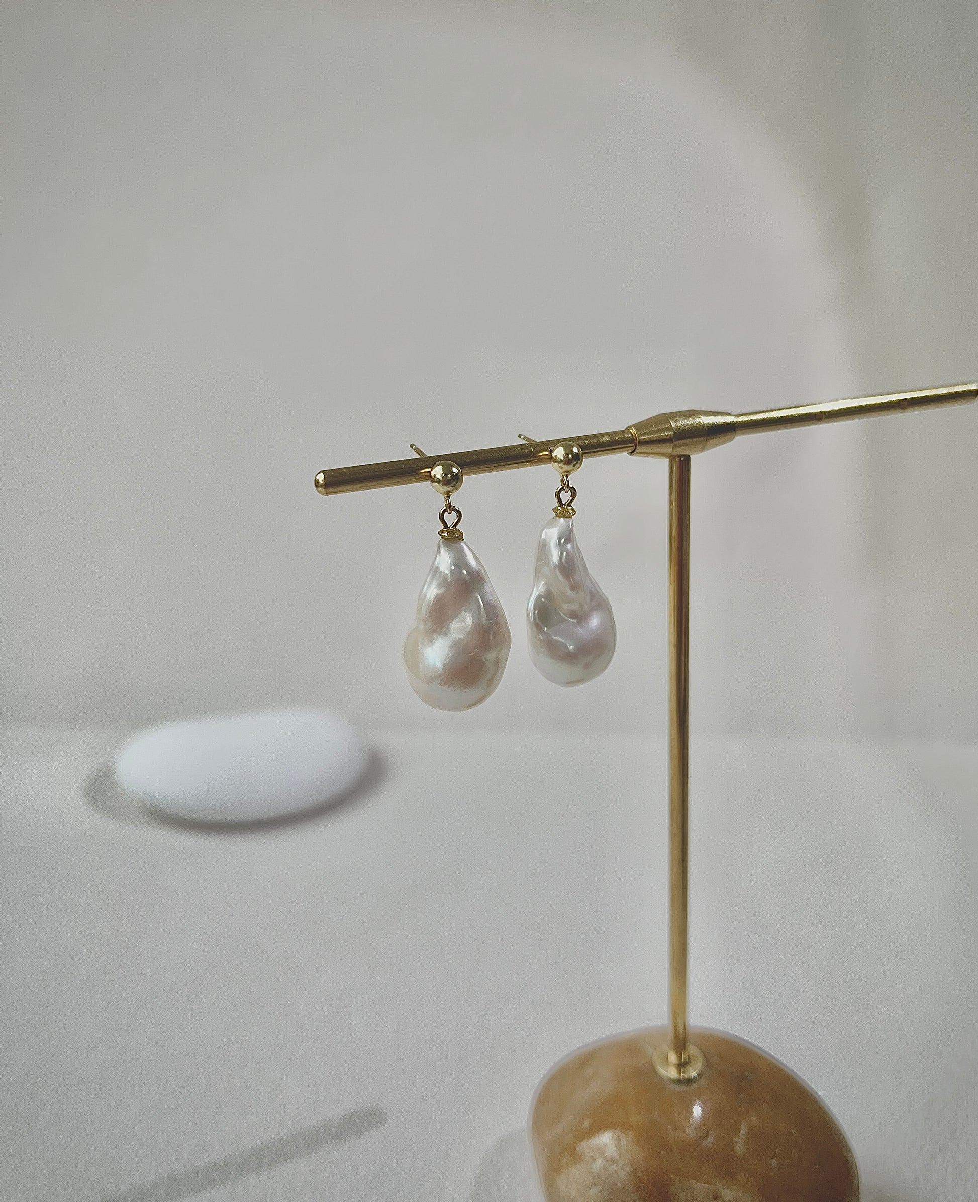 Pearl earrings on a gold stand with a neutral background
