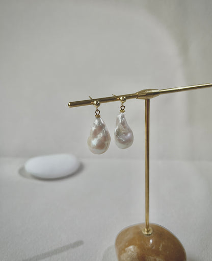 Pearl earrings on a gold stand with a neutral background