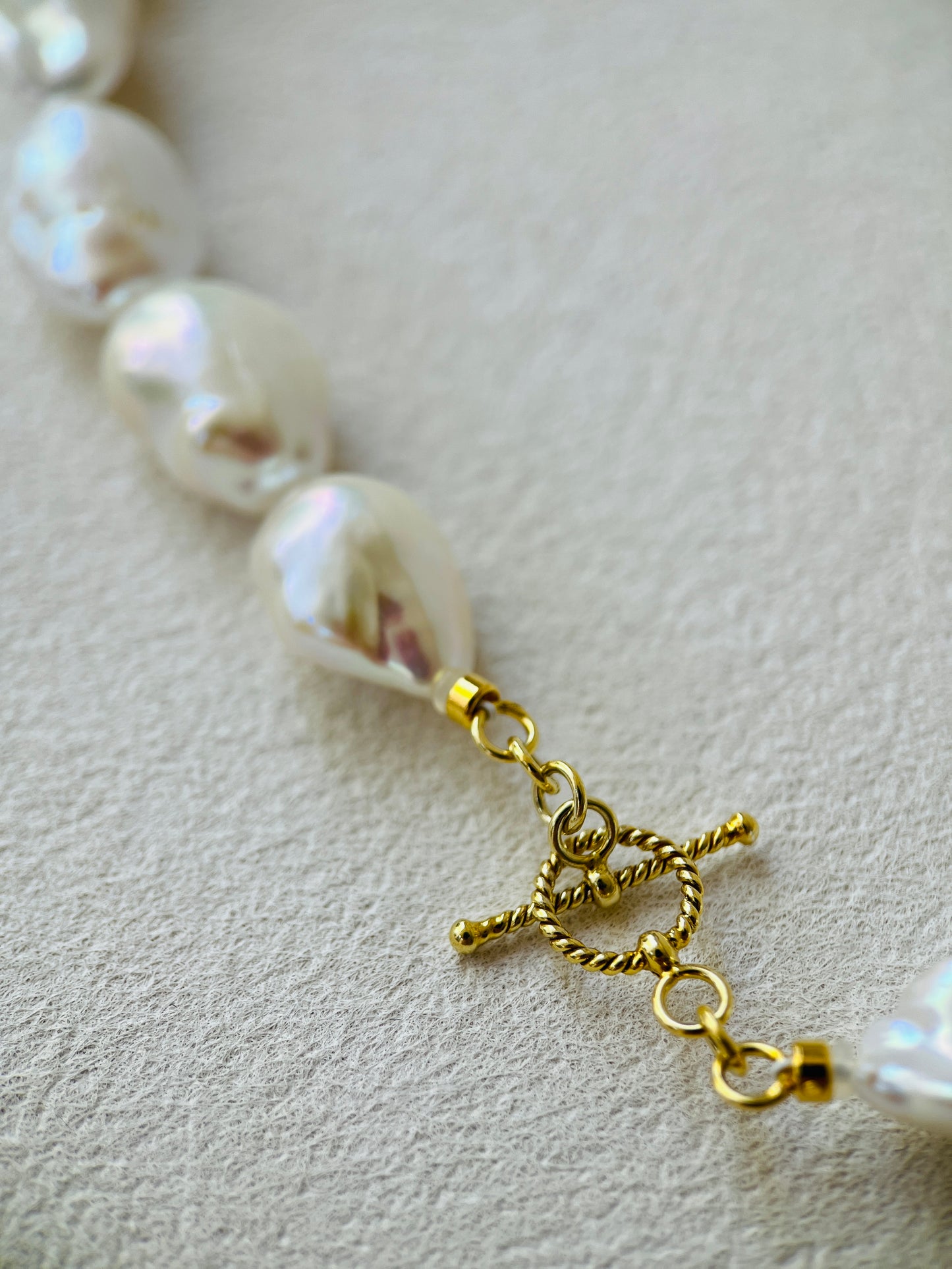 Close-up of the clasp and baroque pearls in a baroque pearl necklace with gold detailing.