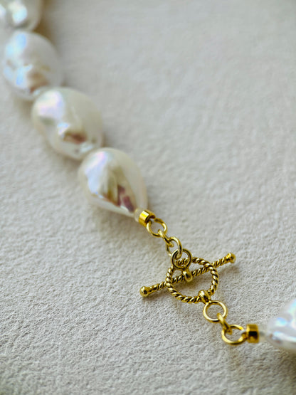 Close-up of the clasp and baroque pearls in a baroque pearl necklace with gold detailing.