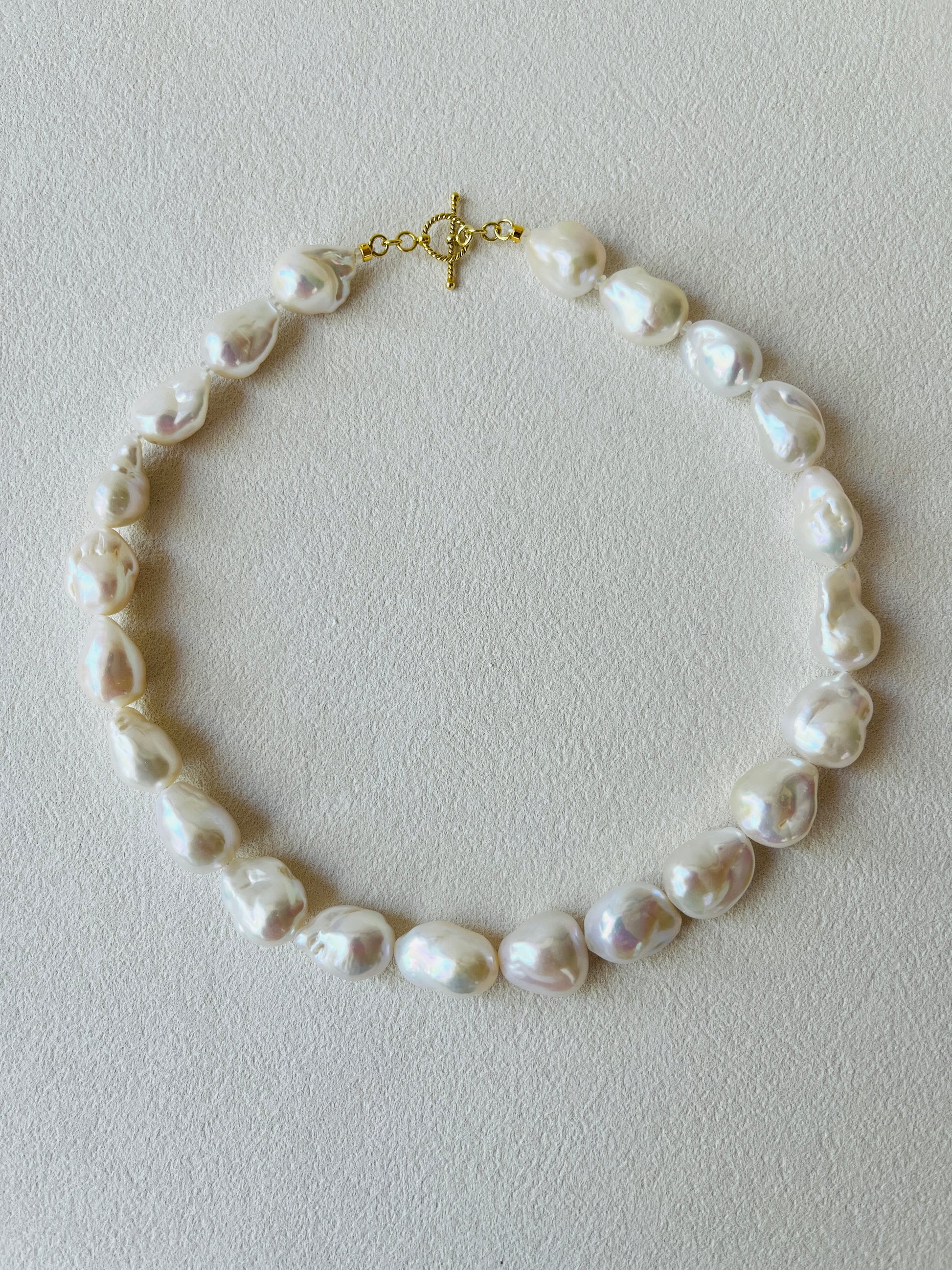 Baroque pearl necklace featuring unique baroque pearls and 24K gold vermeil detailing on a light background.