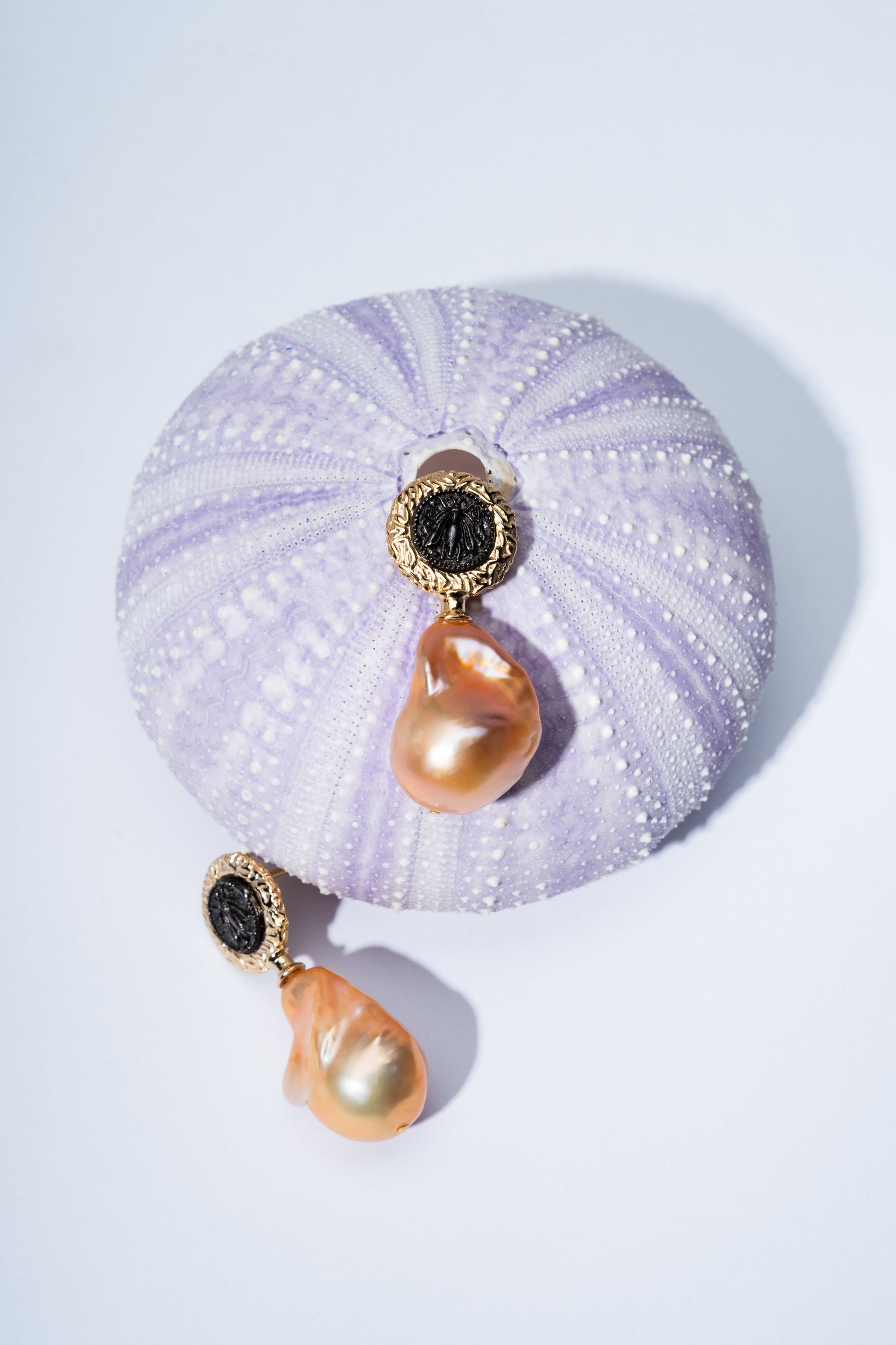 Pair of earrings with gold and black accents on a textured purple surface
