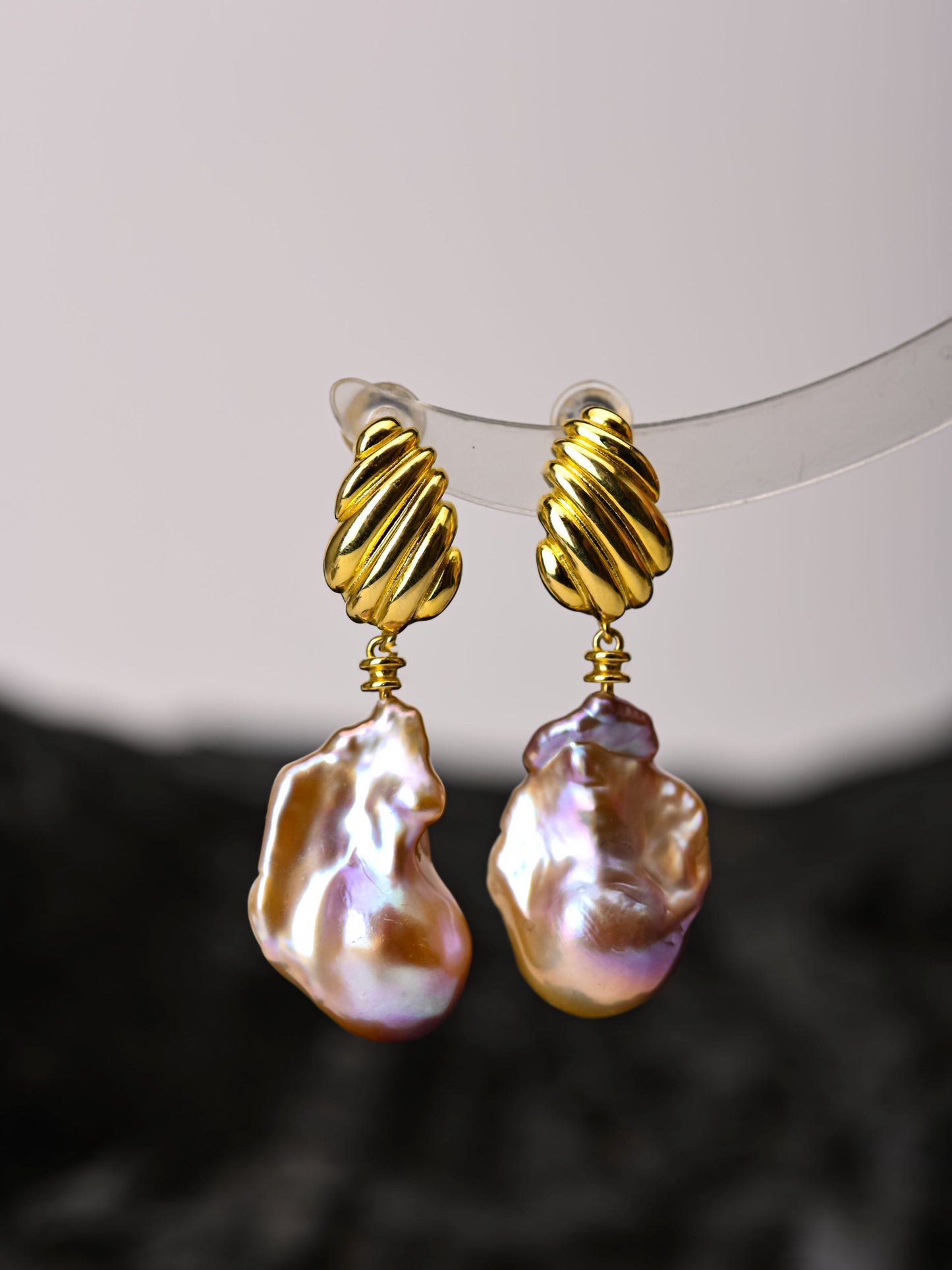 Gold-rimmed baroque pearl earrings on a white background