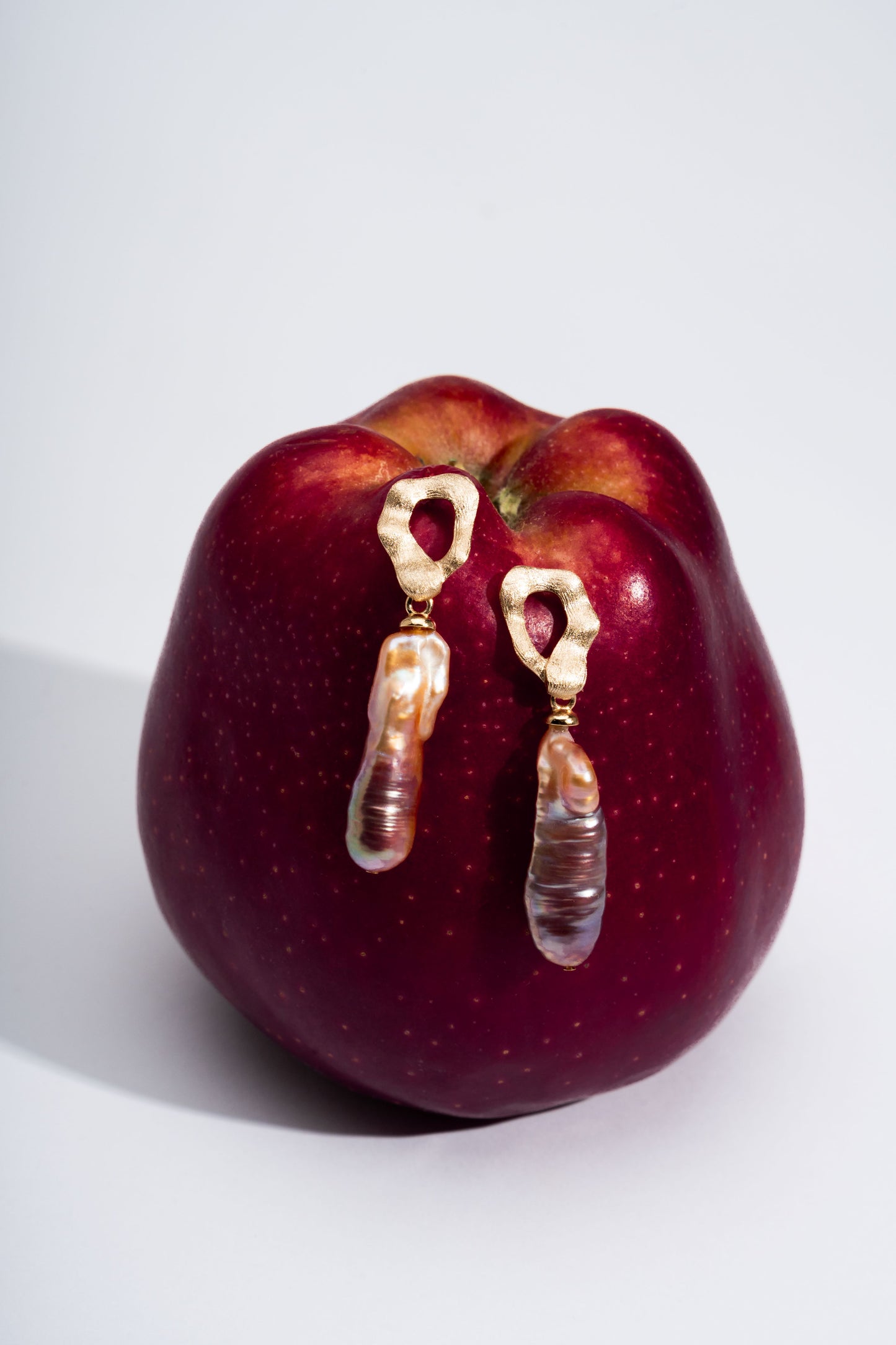 Red apple with gold earrings on a white background