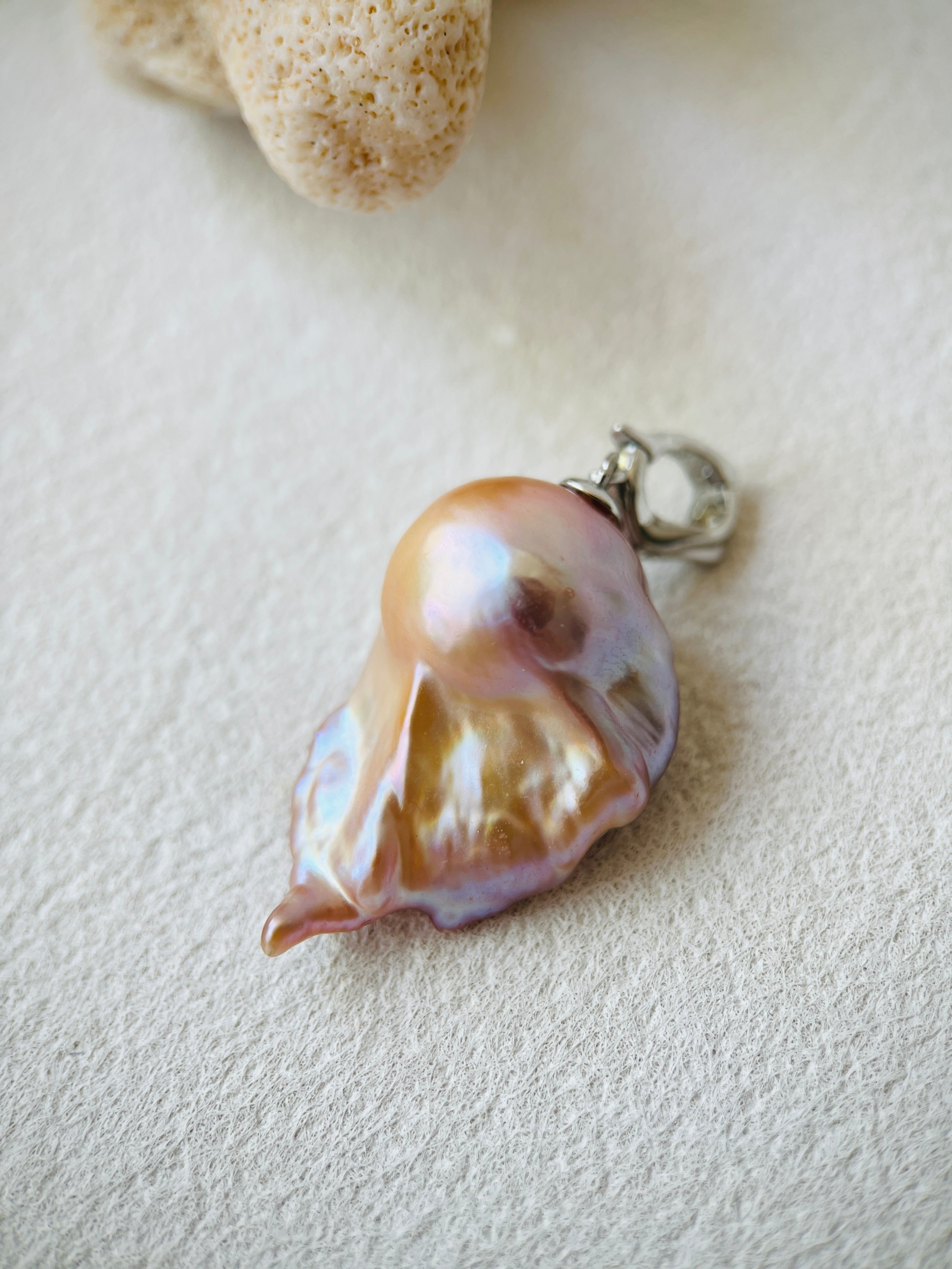 Pearl pendant with a silver clasp on a light background