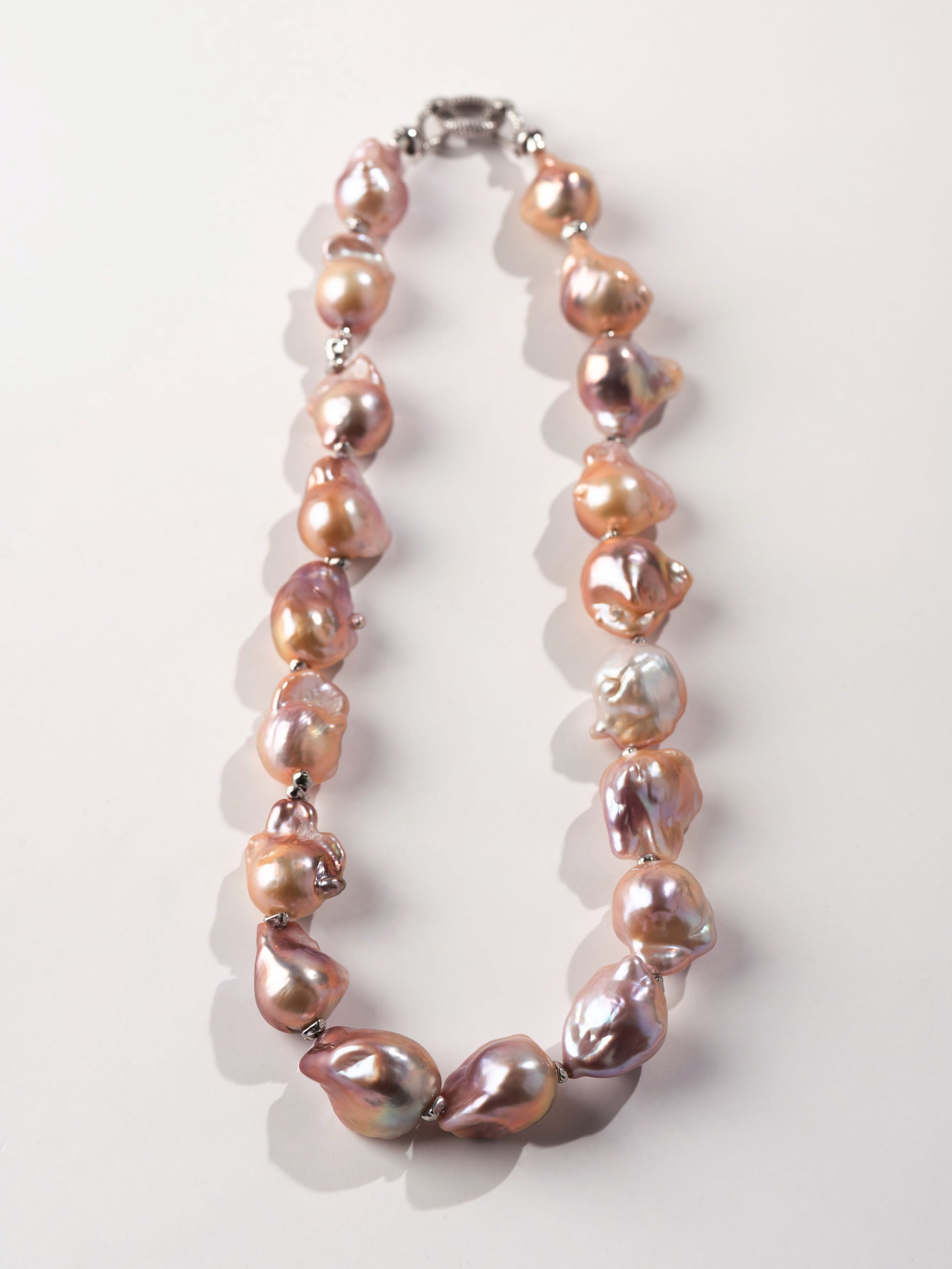 Necklace with pink and brown baroque pearls on a white background