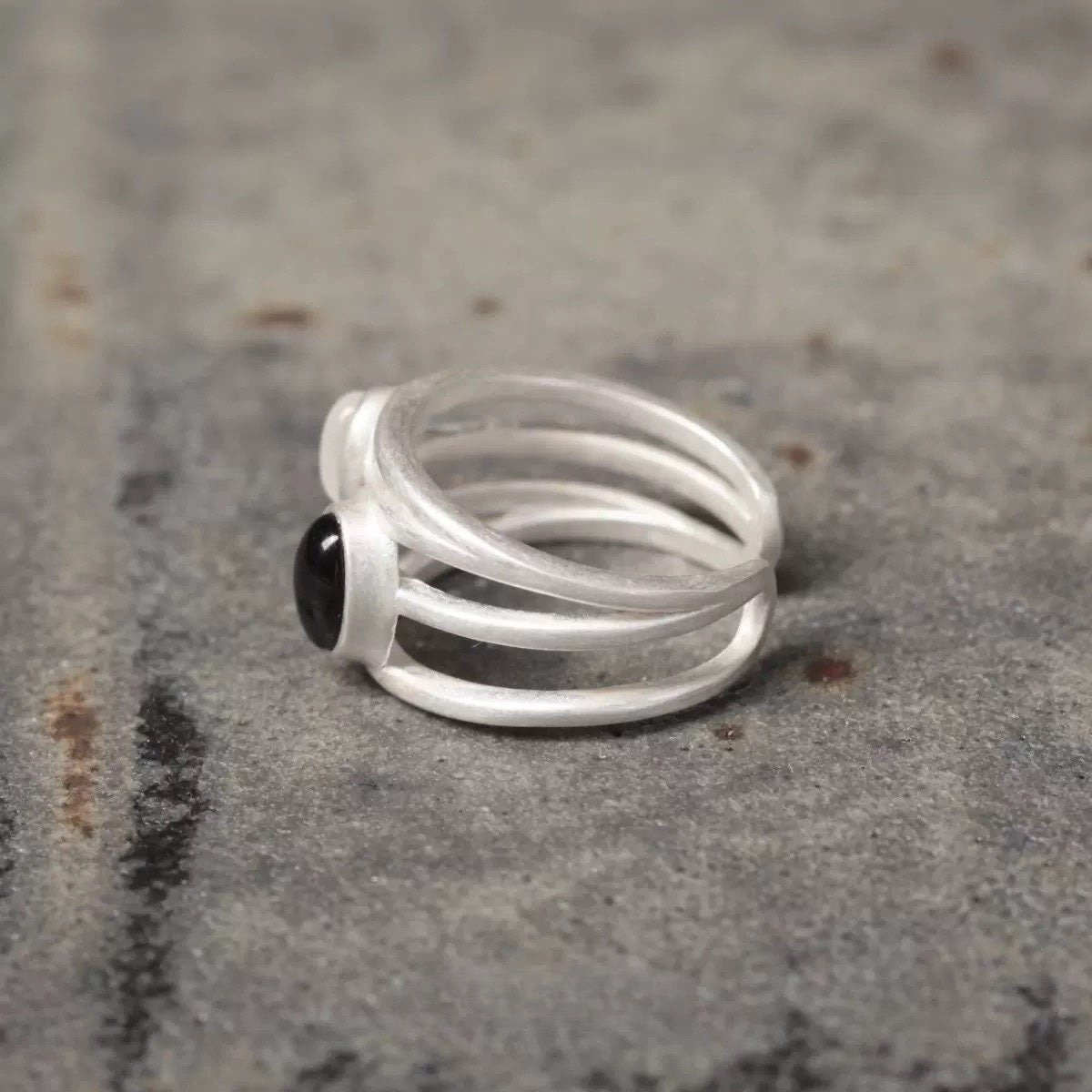 Silver ring with a black gemstone on a textured surface