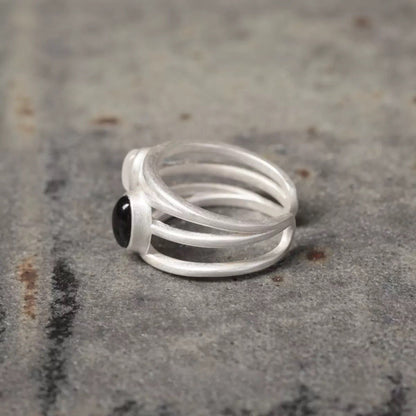 Silver ring with a black gemstone on a textured surface