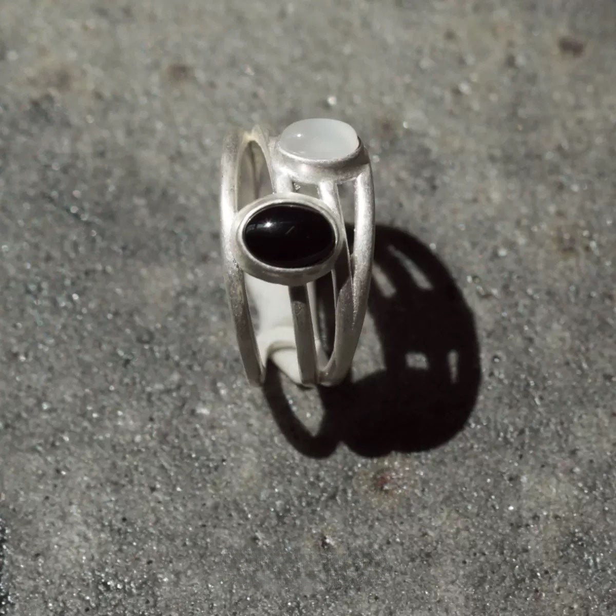 Silver ring with a black stone on a gray surface