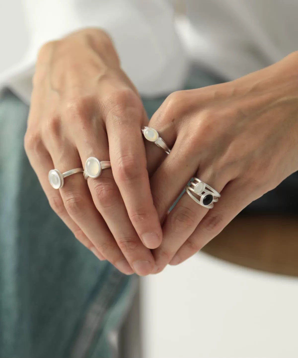 Close-up of hands wearing multiple rings with a neutral background