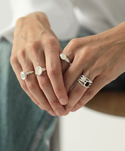 Close-up of hands wearing multiple rings with a neutral background