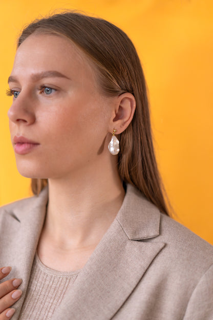Woman wearing pearl earrings against a yellow background