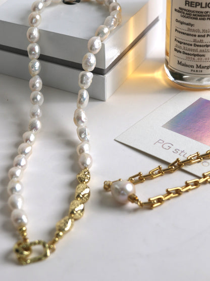 Pearl necklace with gold chain on a white surface with a bottle in the background