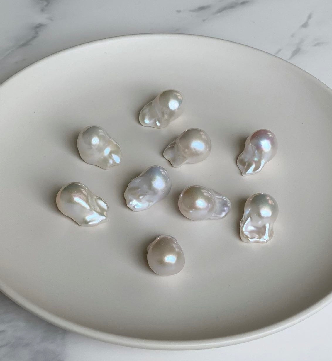 Baroque high luster pearls on a white plate with a marble background