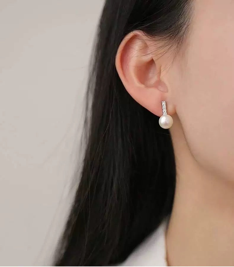 Pearl earring worn by a person with a neutral background